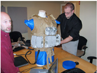 Dr. Evan Goldman (l) and John Ficker of EDGE(r) adjust mockup of vest and body armor for testing sensor system.