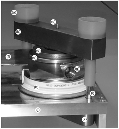 Figure 5. Photograph of a SLAC designed press-pack clamp. (a) G10 electrical isolator, (b) steel clamp, (c) force calibration pin, (d) Belleville springs, (e) steel plate, (f) copper bus, (g) commercial water-cooled heat sink, (h) IGBT, (i) 3/8 grade-8 bolt, (j) commercial heat sink (aluminum blank shown in photograph), (k) steel clamp.